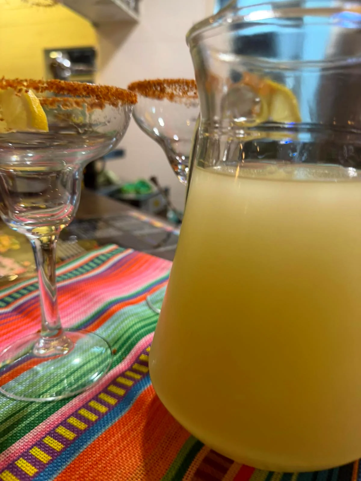 Margaritas en jarra con copas y mantel serape